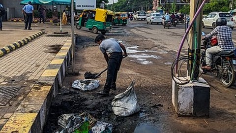 A man employed by Esplanade mall collects waste extracted by BMC workers from storm-water drain at Bomikhal In Bhubaneswar.