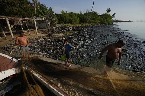 Fishermen spread out their net on the banks of Lake Maracaibo contaminated with oil and trash, in San Francisco, Venezuela.
