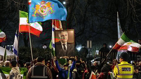 Anti-Iranian regime protesters hold up a portrait of Iranian opposition leader and son of the last shah of Iran Mohammad Reza Pahlavi, Reza Pahlavi (C), as they take part in a demonstration outside the Iranian Embassy in central London on January 10, 2026.