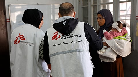 A Palestinian woman arrives with a child at the Doctors Without Borders or Médecins Sans Frontières (MSF) clinic in the al-Rimal neighbourhood of Gaza City on New Year's Eve, December 31, 2025.