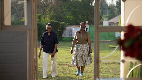Widows Rebecca Anyango, 70 years old, right, and Marie Owino, 87 years old, a former teacher, left, walk outside Marie's compound home in Siaya, Kenya, Thursday, Nov. 27, 2025.