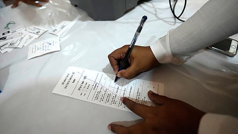 An official of the Union Election Commission checks a sample slip from an electronic voting machine as they prepare to set up a polling station opened at a monastery one day before the second phase of the general election in Yangon, Myanmar, Saturday, Jan. 10, 2026.