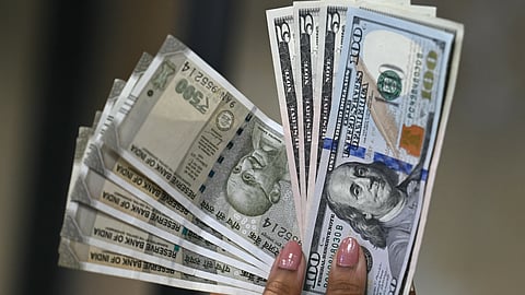 Indian rupee (L) and US dollar currency notes are held by a foreign exchange employee at an office in New Delhi on August 26, 2025.