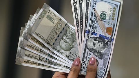 Indian rupee (L) and US dollar currency notes are held by a foreign exchange employee at an office in New Delhi on August 26, 2025.
