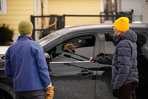 Bystanders film a federal immigration officer in their car Sunday, Jan. 11, 2026, in Minneapolis.