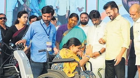 Chief Minister A Revanth Reddy shares a lighter moment with a beneficiary while distributing retrofitted motorized vehicles, battery-powered tricycles and wheelchairs to the disabled at Praja Bhavan in Hyderabad on Monday.