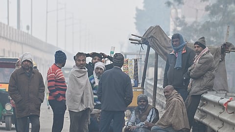 People gather around a roadside bonfire to keep themselves warm on a cold winter morning in New Delhi, Jan 12, 2026.