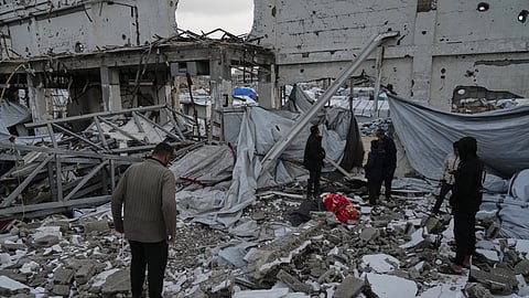 People inspect the site where at least four Palestinians died following the collapse of walls onto tents sheltering displaced people in Gaza City amid rainfall and strong winds, Tuesday, Jan. 13, 2026.
