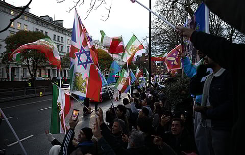 Anti-Iranian regime protesters wave Iranian flags before the 1979 revolution with the Lion and Sun emblems, during a gathering outside the Iranian Embassy, central London, on January 12, 2026.