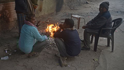 People trying to keep themselves warm by makeshift fire.
