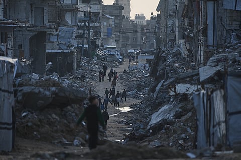 Palestinians walk amid buildings destroyed by Israeli air and ground operations in Gaza City Thursday, Jan. 15, 2026.