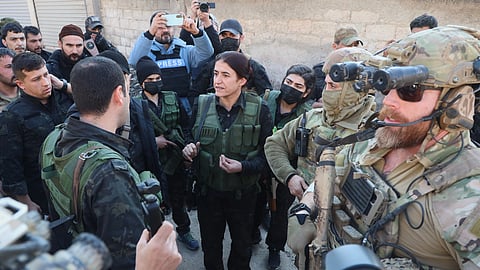 Rohlat Efrin, center, a commander in the US-backed Syrian Democratic Forces, speaks with an SDF member as American soldiers from the US-led coalition against the Islamic State group stand guard during a meeting in Deir Hafer, Syria, Friday, Jan. 16, 2026.