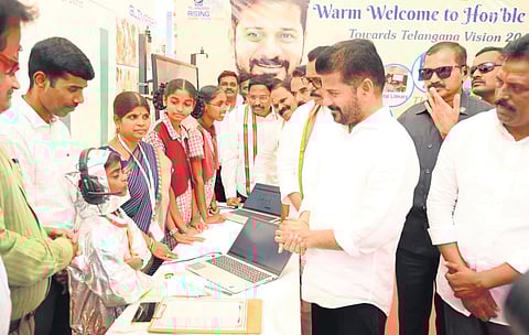 Chief Minister A Revanth Reddy interacts with school students after laying the foundation stone for IIIT at Chittaboinapally in Jadcherla mandal on Saturday