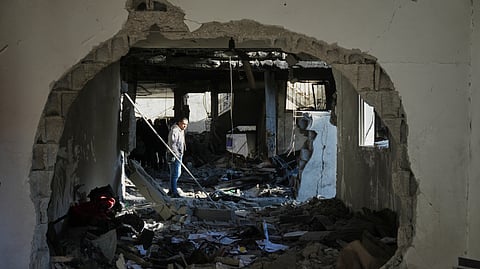 A Palestinian inspects the rubble of the al-Hawli family home, destroyed in an Israeli strike in Deir al-Balah, in the central Gaza Strip, Friday, Jan. 16, 2026.