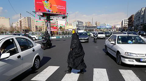 A woman crosses an intersection as vehicles drive past in downtown Tehran, Iran, Friday, Jan. 16, 2026.