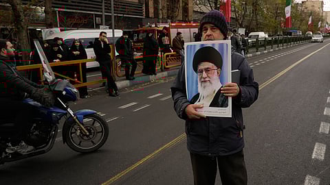 A man holds a poster of the Iranian Supreme Leader Ayatollah Ali Khamenei during a funeral ceremony for a group of security forces, who were killed during anti-government protests, in Tehran, Iran, Wednesday, Jan. 14, 2026