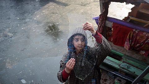 In this photo from Jan. 14, 2026, a kid holds an ice sheet as the temperature plunged to minus 5.2 degrees Celsius during a cold winter morning in Srinagar.