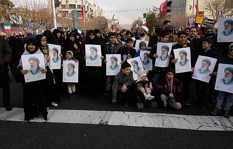 People hold posters of the Iranian Supreme Leader Ayatollah Ali Khamenei during a funeral ceremony for a group of security forces, who were killed during anti-government protests, in Tehran, Iran, Jan. 14, 2026.