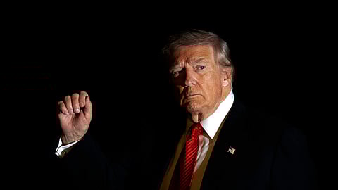 US President Donald Trump is illuminated by a camera flash as he gestures while walking across the South Lawn of the White House, Nov. 2, 2025, in Washington, after returning from a trip to Florida.
