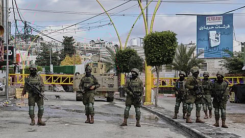 Israeli soldiers take up positions during an army raid in the West Bank city of Hebron Monday.