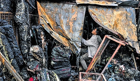 A man checks the condition of his shop after it was reduced to ashes in the fire at Unit-I Market in Bhubaneswar
