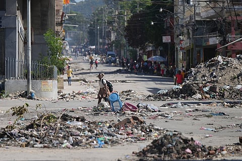 A youth crosses a street littered with garbage in downtown in Port-au-Prince, Haiti, Tuesday, Jan. 20, 2026.