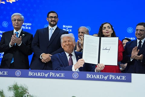 President Donald Trump, center, holds up a signed Board of Peace charter during the Annual Meeting of the World Economic Forum in Davos, Switzerland, Thursday, Jan. 22, 2026.