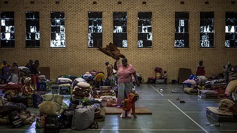 A woman, displaced from the informal settlement of Sporong by the ongoing unrest between the community and a group of artisanal miners commonly referred to as "zama zamas", shakes her blanket.