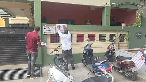 Congress workers sticking posters at the residence of BJP MLA S Suresh Kumar at Rajajinagar in Bengaluru on Saturday.