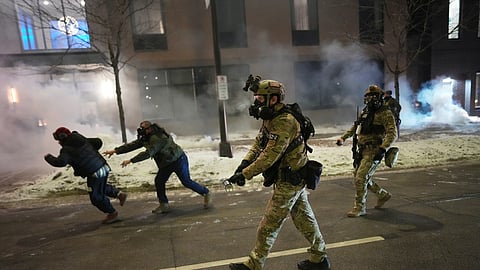 Federal agents try to clear demonstrators near a hotel, using tear gas during a noise demonstration protest in response to federal immigration enforcement operations in the city Sunday, Jan. 25, 2026, in Minneapolis.