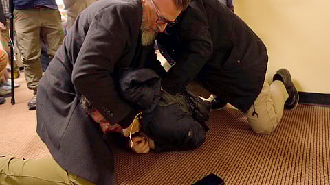 A man is tackled to the ground after spraying an unknown substance on U.S. Rep. Ilhan Omar, D-Minn., during a town hall on Tuesday, Jan. 27, 2026, in Minneapolis.