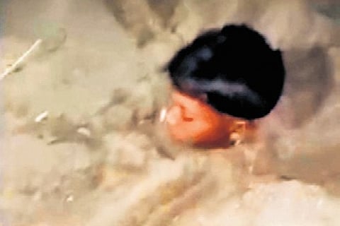Video grab of the minor buried in sand up to his neck on the river bed.