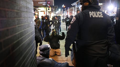 A protester raises their arms on the ground as law enforcement make arrests after declaring an unlawful assembly during a noise demonstration outside the Graduate by Hilton Minneapolis hotel on Wednesday, Jan. 28, 2026, in Minneapolis.