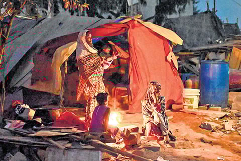 As temperature dips at night, residents of Kogilu keep warm around a bonfire after their houses were demolished during a recent GBA drive
