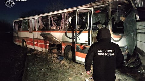 In this photo provided by the Ukrainian Prosecutor's Office, a war crimes prosecutor examines the damaged coal miners bus that was hit by Russian drone in Dnipropetrovsk region.