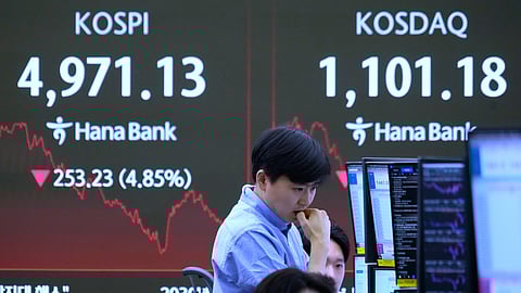A currency trader watches monitors near a screen showing the Korea Composite Stock Price Index (KOSPI), left, at the foreign exchange dealing room of the Hana Bank headquarters in Seoul, South Korea, Monday, Feb. 2, 2026.