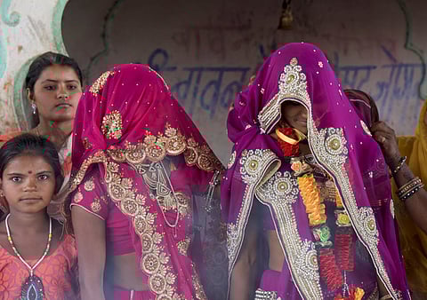 An underaged bride standing with her family during wedding rituals at a temple near Rajgarh, Madhya Pradesh