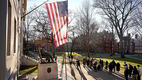 People take photos near a John Harvard statue, left, on the Harvard University campus, Jan. 2, 2024, in Cambridge, Mass.