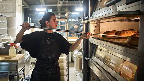 Olha Hrynchuk, 28, owner of a bakery, bakes bread early morning running on a generator during a blackout caused by Russia's regular air attacks on the country's energy system Friday, Jan. 30, 2026, in Kyiv.