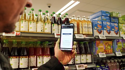 Ian Rosenfeldt, the creator of the "Made O'Meter" mobile app, demonstrates how shoppers can use the application in different languages to identify and boycott American goods in a grocery store in Copenhagen, Wednesday, Jan. 28, 2026.