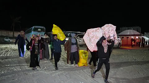 Palestinians carry the belongings of relatives arriving in Gaza from Egypt following the long-awaited reopening of the Rafah border crossing, in Khan Younis, southern Gaza Strip, early Thursday, Feb. 5, 2026.