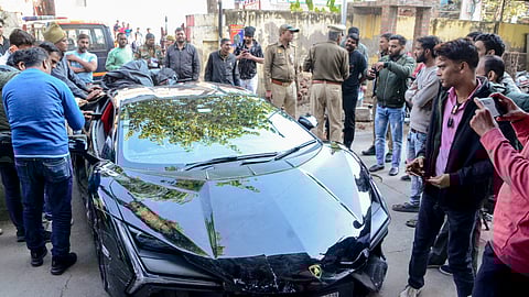 People gather around a Lamborghini car which collided with a rickshaw, injuring three people, in Kanpur, Sunday, Feb. 8, 2026.
