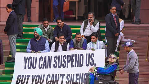 Congress MP Shashi Tharoor, front right, arrives in a wheelchair as Lok Sabha MPs who were suspended from the Lok Sabha on Tuesday protest outside the Parliament.