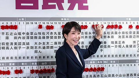Japanese Prime Minister Sanae Takaichi places a red paper rose on the name of an elected candidate at LDP headquarters in Tokyo during parliamentary elections Sunday