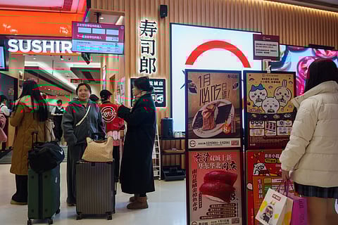 Customers wait outside a store for Sushiro, a Japan-based conveyor-belt sushi chain, in Beijing, Wednesday, Jan. 14, 2026.