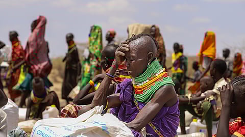 An elderly Turkana woman covers herself from the hot sun after receiving her food ration, in Lomeluku Village, Turkana County, Kenya, Sunday, Feb. 8, 2026.