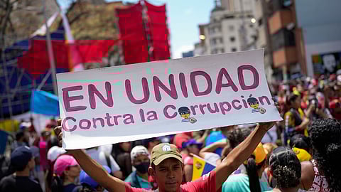 A government supporter holds a sign with a message that reads in Spanish: "In unity against corruption," during a rally against corruption in Caracas, Venezuela, Saturday, March 25, 2023.