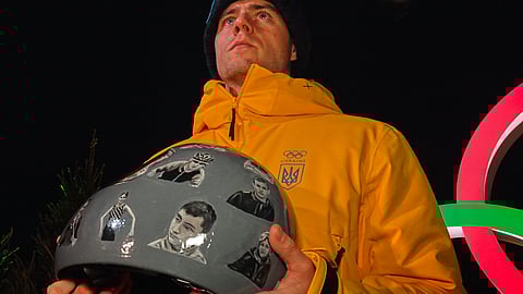 Ukraine's Vladyslav Heraskevych holds up his crash helmet during a press conference following a skeleton training session at the 2026 Winter Olympics, in Cortina d'Ampezzo, Italy, Tuesday, Feb. 10, 2026.