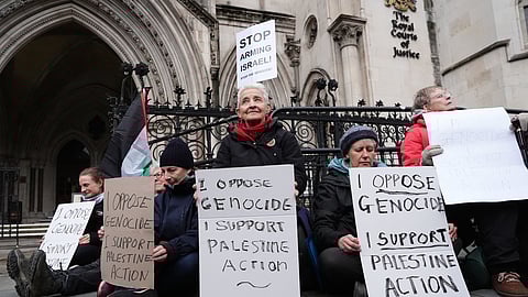 Protesters hold placards outside the High Court, in London, Friday, Feb. 13, 2026, where Judges ruled in favor of Palestine Action's co-founder Huda Ammori's challenge over the ban of the organisation as a terror group.