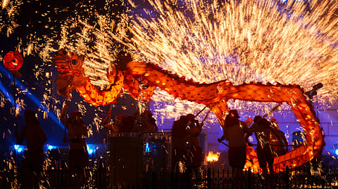Fire performers carry a dragon during a molten iron fireworks performance known as "fire dragon steel flowers" ahead of Lunar New Year celebrations at an amusement park on the outskirts of Beijing, China, Saturday, Feb. 14, 2026.